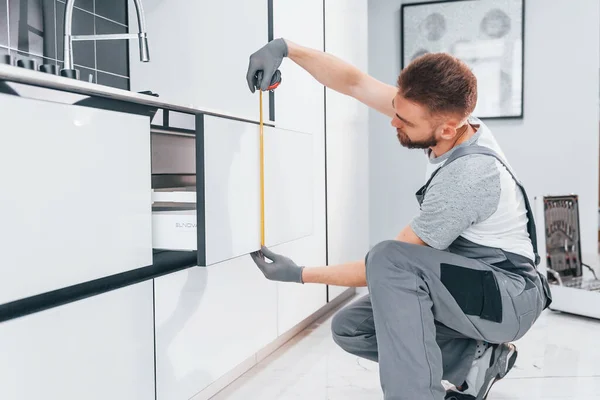 Young Professional Plumber Grey Uniform Measuring Table Using Meter Kitchen — Zdjęcie stockowe