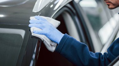 Yeni modern arabaları cilalayan üniformalı bir erkek işçi. Hizmet kavramı.