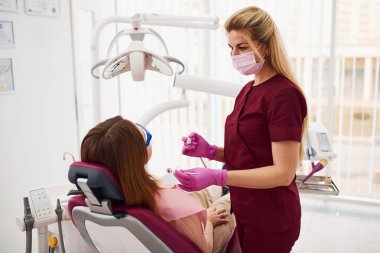 Koruyucu gözlüklü küçük kız klinikteki dişçiyi ziyaret ediyor. Stomatoloji kavramı.