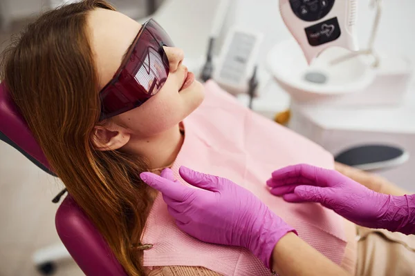 Koruyucu gözlüklü küçük kız klinikteki dişçiyi ziyaret ediyor. Stomatoloji kavramı.