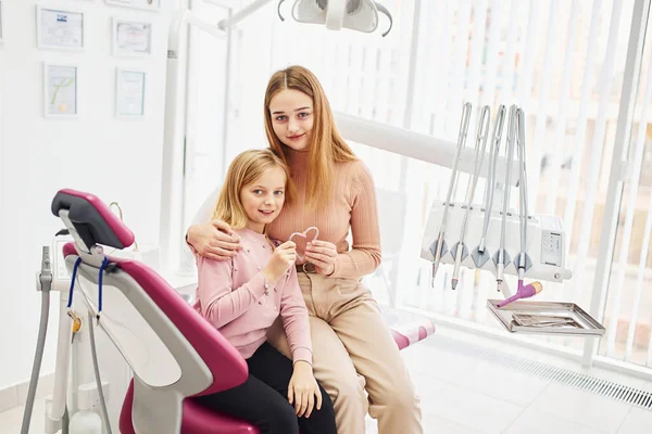 Küçük bir kız annesiyle kliniğe dişçiye gidiyor. Stomatoloji kavramı.