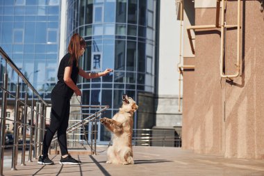 Koruyucu maskeli genç bir kadın karantina zamanında iş yerinin yakınında dışarıda yürüyüş yapıyor. Koronavirüs kavramı.