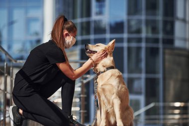 Koruyucu maskeli genç bir kadın karantina zamanında iş yerinin yakınında dışarıda yürüyüş yapıyor. Koronavirüs kavramı.