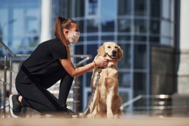 Koruyucu maskeli genç bir kadın karantina zamanında iş yerinin yakınında dışarıda yürüyüş yapıyor. Koronavirüs kavramı.