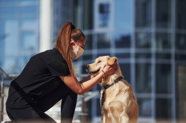 Koruyucu maskeli genç bir kadın karantina zamanında iş yerinin yakınında dışarıda yürüyüş yapıyor. Koronavirüs kavramı.
