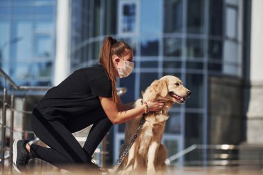 Koruyucu maskeli genç bir kadın karantina zamanında iş yerinin yakınında dışarıda yürüyüş yapıyor. Koronavirüs kavramı.