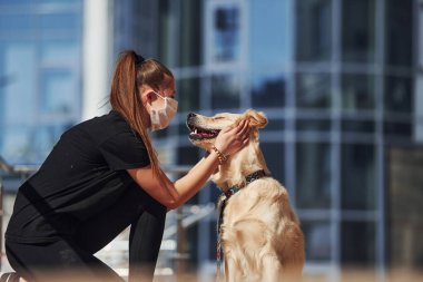 Koruyucu maskeli genç bir kadın karantina zamanında iş yerinin yakınında dışarıda yürüyüş yapıyor. Koronavirüs kavramı.