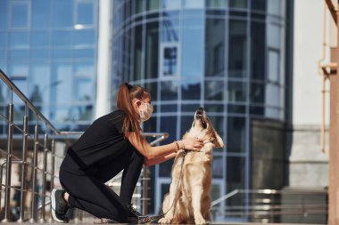 Koruyucu maskeli genç bir kadın karantina zamanında iş yerinin yakınında dışarıda yürüyüş yapıyor. Koronavirüs kavramı.