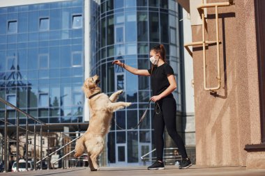 Koruyucu maskeli genç bir kadın karantina zamanında iş yerinin yakınında dışarıda yürüyüş yapıyor. Koronavirüs kavramı.