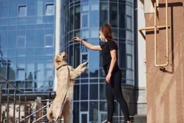 Koruyucu maskeli genç bir kadın karantina zamanında iş yerinin yakınında dışarıda yürüyüş yapıyor. Koronavirüs kavramı.