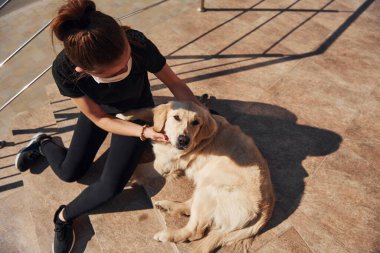 Koruyucu maskeli genç bir kadın karantina zamanında iş yerinin yakınında dışarıda yürüyüş yapıyor. Koronavirüs kavramı.