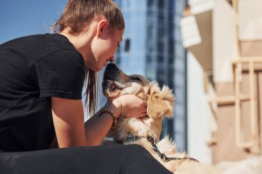 Birbirinize sarılın. Genç, pozitif bir kadın iş binasının yanında dışarıda dolaşırken köpeğiyle eğleniyor..