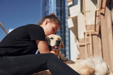 Birbirinize sarılın. Genç, pozitif bir kadın iş binasının yanında dışarıda dolaşırken köpeğiyle eğleniyor..