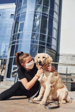 Koruyucu maskeli genç bir kadın karantina zamanında iş yerinin yakınında dışarıda yürüyüş yapıyor. Koronavirüs kavramı.