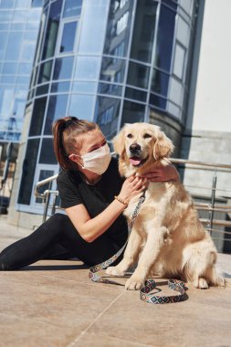 Koruyucu maskeli genç bir kadın karantina zamanında iş yerinin yakınında dışarıda yürüyüş yapıyor. Koronavirüs kavramı.