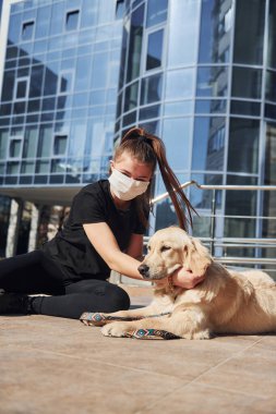 Koruyucu maskeli genç bir kadın karantina zamanında iş yerinin yakınında dışarıda yürüyüş yapıyor. Koronavirüs kavramı.