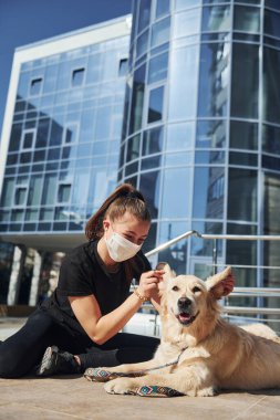 Koruyucu maskeli genç bir kadın karantina zamanında iş yerinin yakınında dışarıda yürüyüş yapıyor. Koronavirüs kavramı.