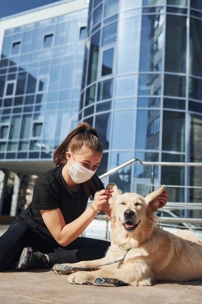 Koruyucu maskeli genç bir kadın karantina zamanında iş yerinin yakınında dışarıda yürüyüş yapıyor. Koronavirüs kavramı.