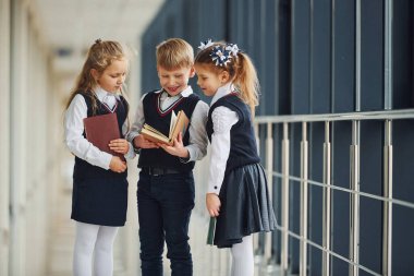 School kids in uniform together with books in corridor. Conception of education.