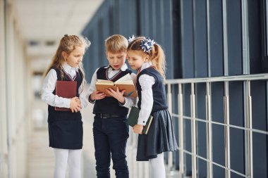 School kids in uniform together with books in corridor. Conception of education.