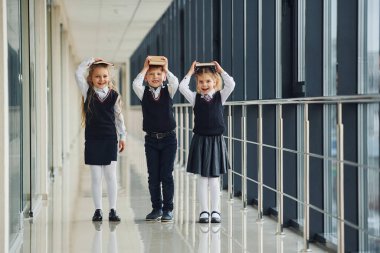 School kids in uniform together with books in corridor. Conception of education.