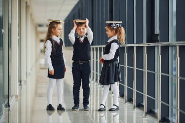 School kids in uniform together with books in corridor. Conception of education.