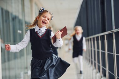 Active school kids in uniform running together in corridor. Conception of education.