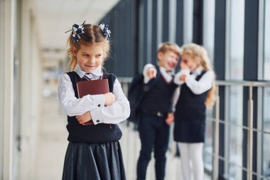 Küçük kız zorbalığa uğruyor. Taciz kavramı. Okul çocukları koridorda birlikte üniforma giyiyorlar..