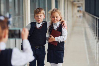 Okul üniformalı çocuklar koridorda fotoğraf çekiyorlar. Eğitim kavramı.