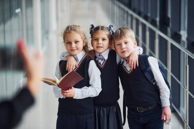 Okul üniformalı çocuklar koridorda fotoğraf çekiyorlar. Eğitim kavramı.