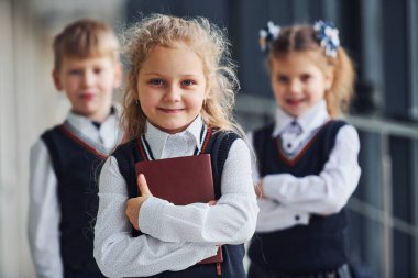 School kids in uniform together with books in corridor. Conception of education.