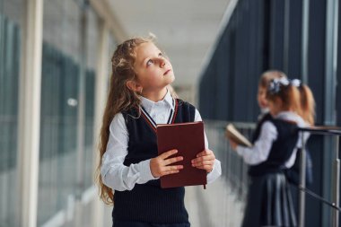 School kids in uniform together with books in corridor. Conception of education.