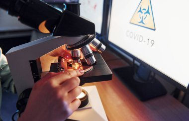 Laboratuvarda mikroskopla çalışan insanın ellerine yakından bakın. Koronavirüs kavramı.