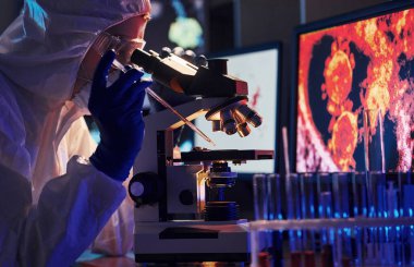 Beyaz koruyucu üniforma giyen bilim adamları verilerle birlikte laboratuvarda koronavirüs ve kan tüpleriyle çalışıyorlar..