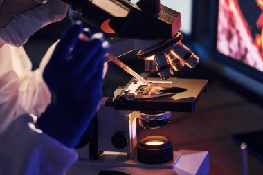 Beyaz koruyucu üniformalı bilim adamları laboratuarda koronavirüs ve kan tüpleriyle çalışıyorlar..