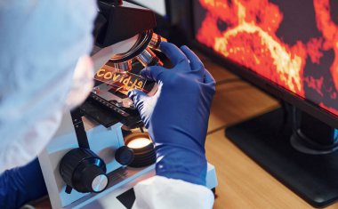 Beyaz koruyucu bilimadamları laboratuvarda kapalı alanda COVID-19 başlıklı lens takıyorlar..