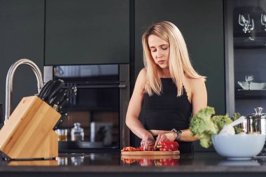 Güzel sarışın mutfakta duruyor ve yemek hazırlıyor..
