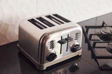 Close up view of silver colored toaster that standing on gas stove indoors in kitchen.