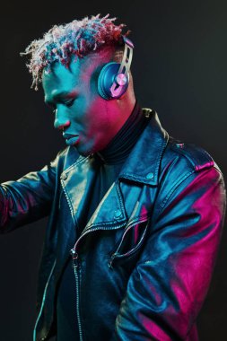 Kulaklıkla dans etmek. Fütürist neon ışıkları. Stüdyodaki Afrikalı Amerikalı genç adam..