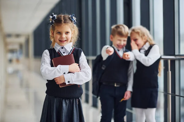 小女孩被欺负了骚扰的概念 在走廊里穿制服的学童在一起 — 图库照片