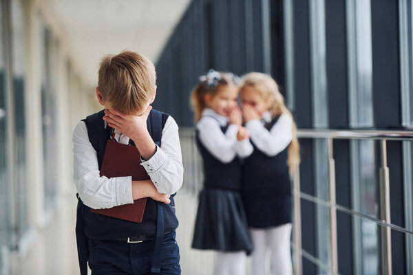 Little boy gets bullied. Conception of harassment. School kids in uniform together in corridor.
