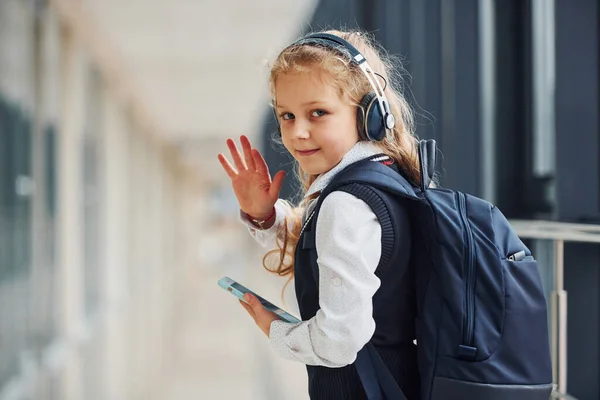 Cute Little School Girl Uniform Headphones Phone Indoors —  Fotos de Stock