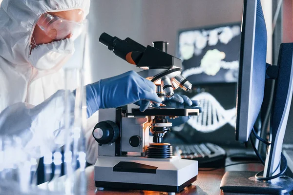 Side view of scientist in white protective uniform that works with coronavirus in laboratory.