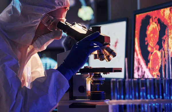 Beyaz koruyucu üniforma giyen bilim adamları verilerle birlikte laboratuvarda koronavirüs ve kan tüpleriyle çalışıyorlar..