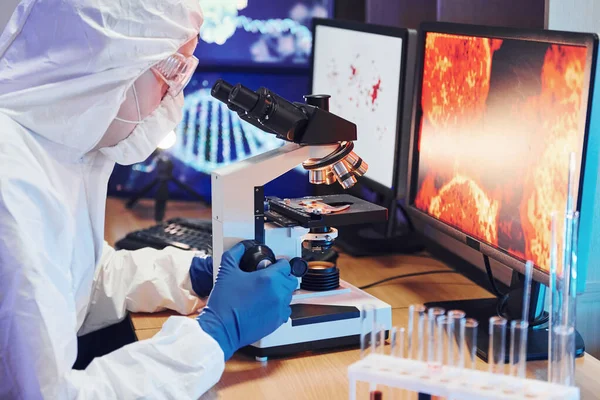 Beyaz koruyucu üniforma giyen bilim adamları verilerle birlikte laboratuvarda koronavirüs ve kan tüpleriyle çalışıyorlar..