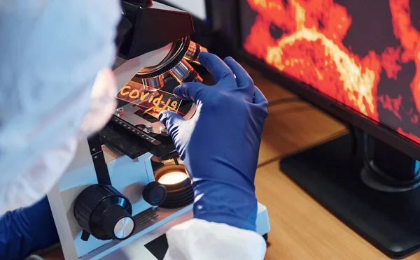 Beyaz koruyucu bilimadamları laboratuvarda kapalı alanda COVID-19 başlıklı lens takıyorlar..