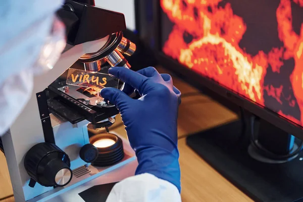 Beyaz korumalı bilim adamları laboratuarda üzerinde virüs başlığı bulunan mercekleri giyerler..