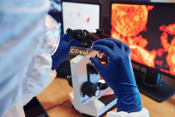 Beyaz koruyucu bilimadamları laboratuvarda kapalı alanda COVID-19 başlıklı lens takıyorlar..