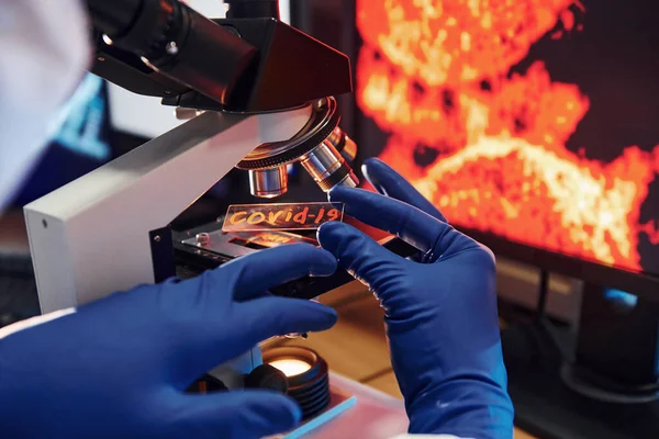 Beyaz koruyucu bilimadamları laboratuvarda kapalı alanda COVID-19 başlıklı lens takıyorlar..