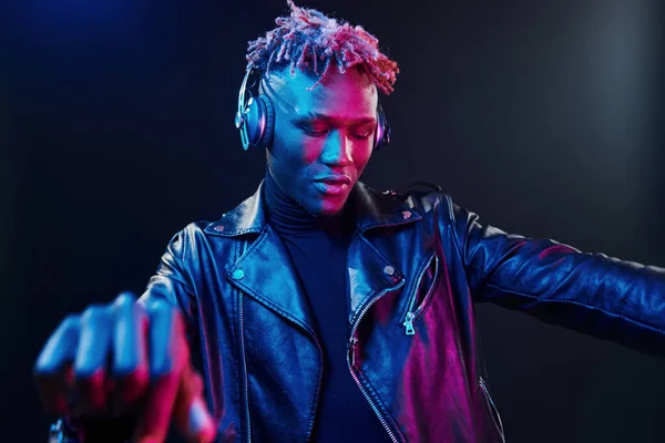 Kulaklıkla dans etmek. Fütürist neon ışıkları. Stüdyodaki Afrikalı Amerikalı genç adam..
